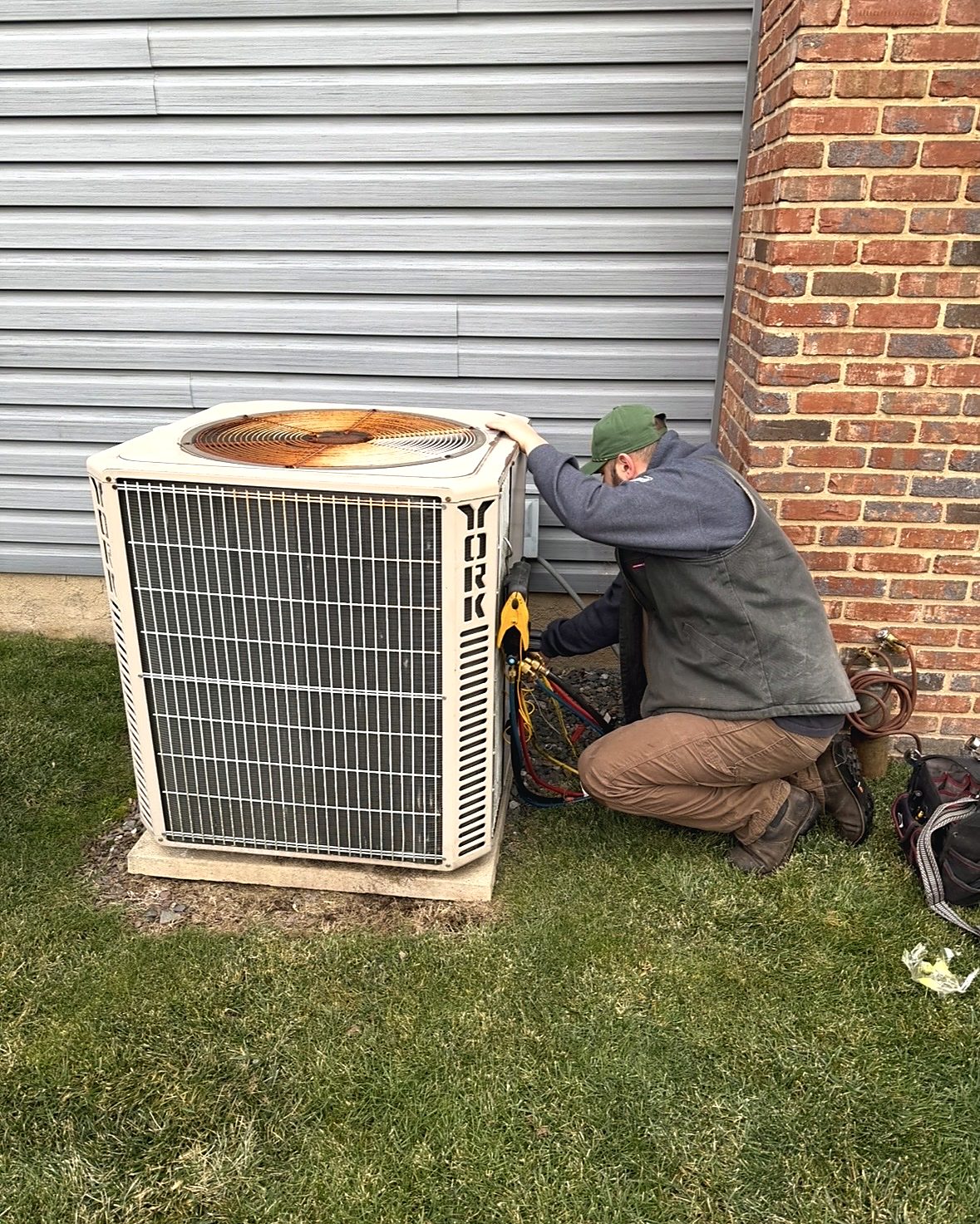 Evan, owner of Edge Mechanical, kneeling beside a York condenser with manifold gauges